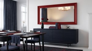 Grand miroir encadré rouge au-dessus d'un buffet bleu marine dans salle à manger moderne. Table dressée en premier plan.