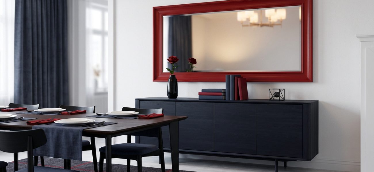 Grand miroir encadré rouge au-dessus d'un buffet bleu marine dans salle à manger moderne. Table dressée en premier plan.